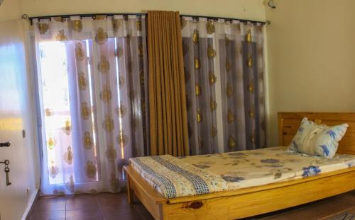 a bedroom with a bed and a window with curtains at Villa Soa in Antananarivo