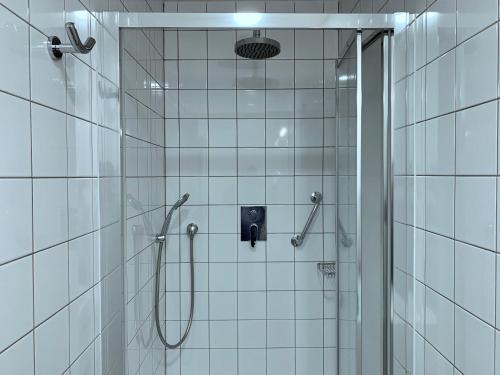 a shower in a bathroom with white tiles at Marienbad Apartment in Mariánské Lázně