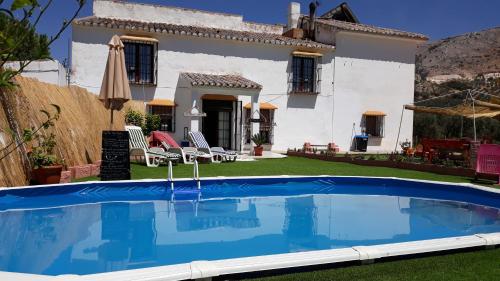una villa con piscina di fronte a una casa di Cortijo la Dehesa del Trabuco a Villanueva del Trabuco