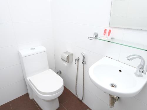 a white bathroom with a toilet and a sink at Elite Hotel in Kuantan