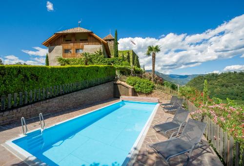 a swimming pool with two chairs and a house at Apartments Schloss Warth in Appiano sulla Strada del Vino