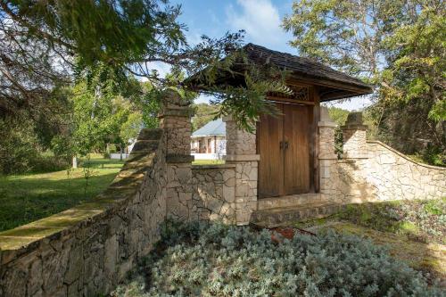 a stone building with a wooden door on a wall at Garden Pavilion - Art House Yallingup in Yallingup