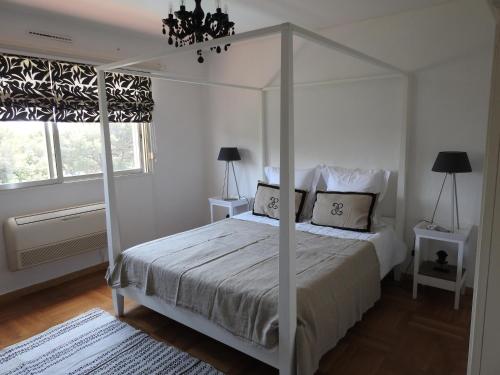 1 dormitorio con cama blanca con dosel y ventana en La Cavale En Mer T5 160m², en Cavalaire-sur-Mer