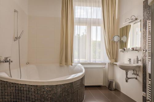 een witte badkamer met een bad en een wastafel bij Zámeček Petrovice in Petrovice u Karviné