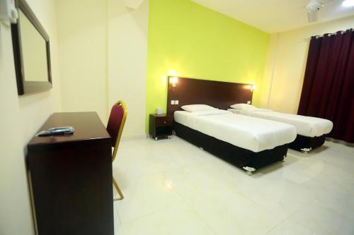 a hotel room with two beds and a desk at Al Dhiyafa Palace Hotel Apartments قصر الضيافة للشقق الفندقية in Muscat