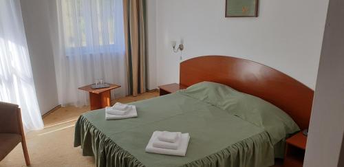 a bedroom with a bed with two towels on it at HELIOS in Ocna Sibiului