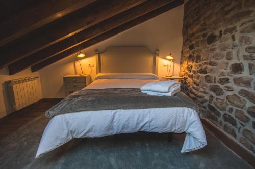 a bed in a room with a stone wall at Palomba Rural in Espinilla