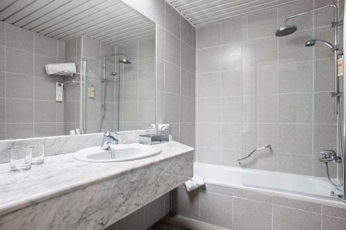 
a bathroom with a tub, sink and mirror at Sol Pelicanos Ocas in Benidorm
