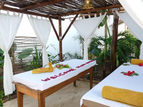 two beds in a room with a view of the ocean at Aluna Nungwi in Nungwi