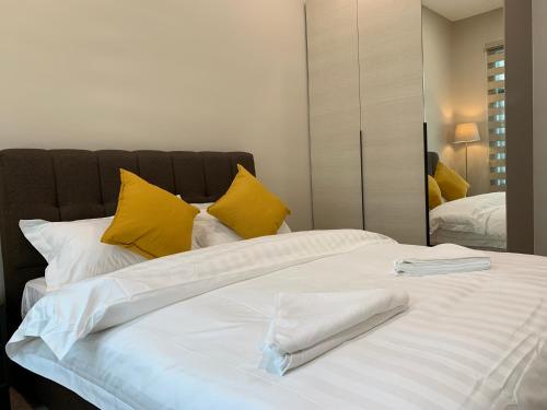 ein großes weißes Bett mit gelben Kissen und einem Spiegel in der Unterkunft SweetHome 3BR@P'Residence Apartment 1226Sft 6 in Kuching