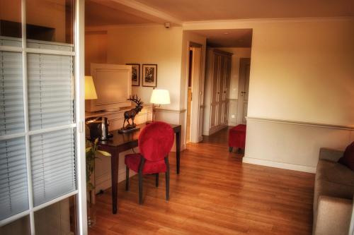 a living room with a desk and red chairs at Parkhotel Surenburg in Hörstel