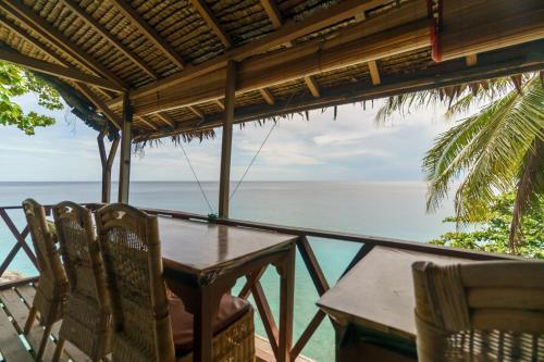 a table and chairs on a balcony overlooking the ocean at RedDoorz Syariah at Sumur Tiga Beach Sabang Aceh in Sabong