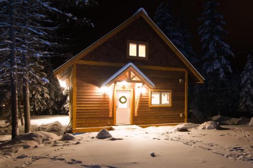 a cabin with a lighted door in the snow at night at Cedar House Restaurant & Chalets in Golden