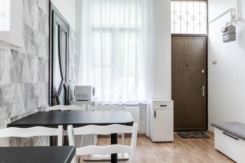 jadalnia z czarnym stołem i białymi krzesłami w obiekcie InshiApartments on Bohomolʹtsya str w Lwowie