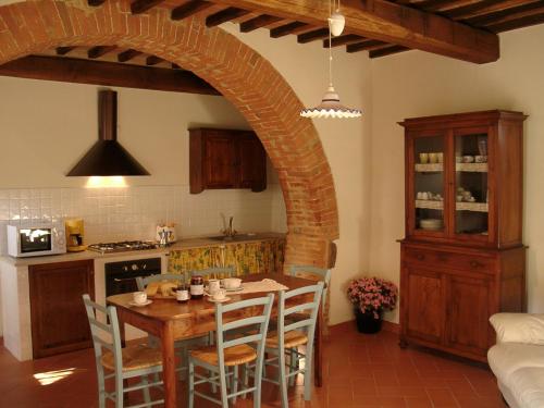 モンテプルチャーノにあるFrateria Di San Benedettoのキッチン(テーブル、椅子、アーチ付)