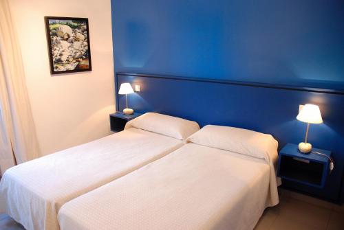 a blue bedroom with a bed and two lamps at Hostal El Cardenillo in Madrigal de la Vera