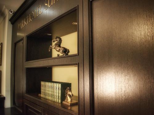 a shelf with a book and a horse in a room at Parkhotel Surenburg in Hörstel