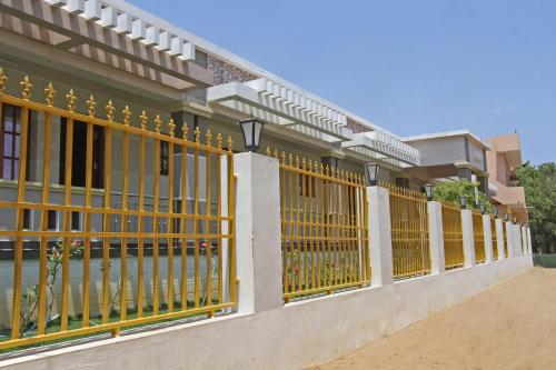 a fence with yellow gates in front of a building at VLS Holiday Home in Kanyakumari