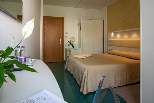 una camera d'albergo con due letti e un tavolo con un fiore di Hotel Mar Del Plata a Grado