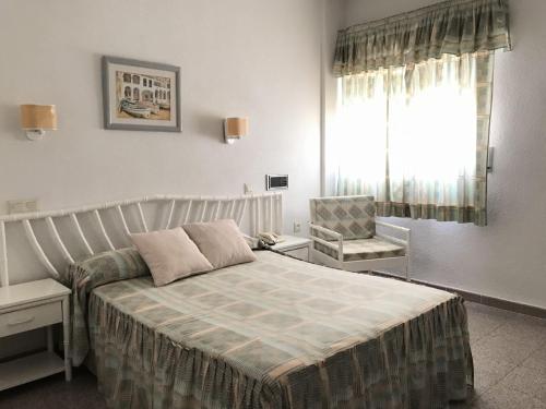 a bedroom with a bed and a chair and a window at Hotel las Conchas in La Rábita