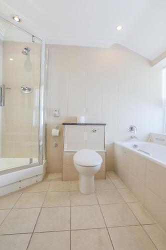 a bathroom with a toilet and a tub and a sink at Claremont Hotel in Douglas