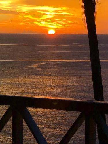 a sunset over the ocean with a fence at Castara Inn in Castara