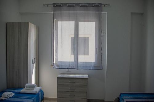 a bedroom with a window and a dresser and a bed at Case Vacanze Blue Sea in Mascali