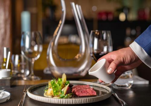 a person holding a plate of food on a table at Hotel & Spa Savarin - Rijswijk, The Hague in Rijswijk