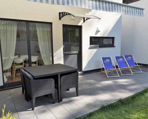 a patio with a black table and blue chairs at Przystanek Wczasy in Jastarnia