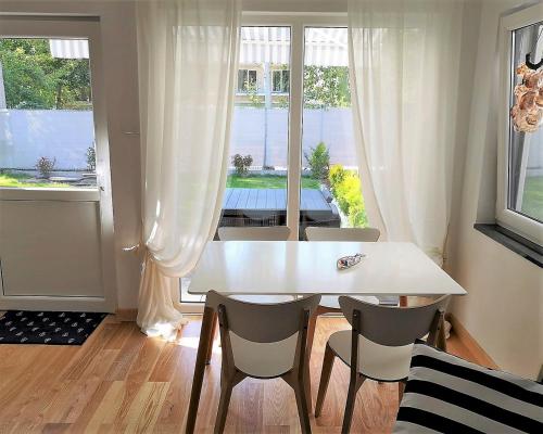 una mesa y sillas blancas en una habitación con ventana en Przystanek Wczasy, en Jastarnia