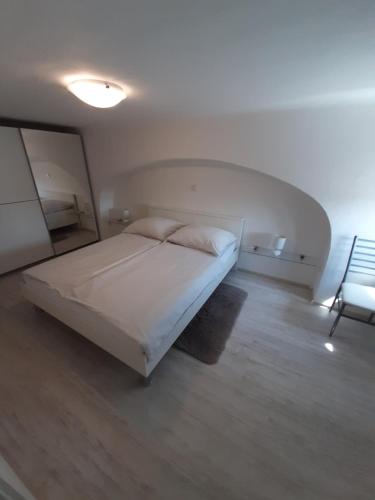 um quarto com uma cama branca e uma cadeira em Apartment Osk em Osijek