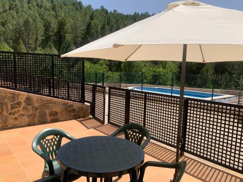 einen Tisch und Stühle unter einem Sonnenschirm neben einem Pool in der Unterkunft Apartamento Rural Sierra de Segura in Segura de la Sierra