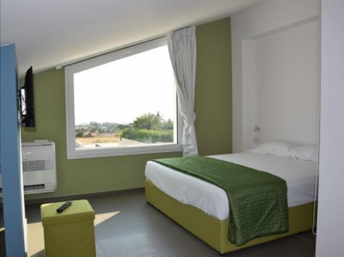 a bedroom with a bed and a large window at Villa Arillà con piscina e padel in Marina di Ragusa