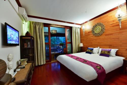 a bedroom with a large bed and a television at Xishuangbanna Elephant Home Guesthouse in Jinghong