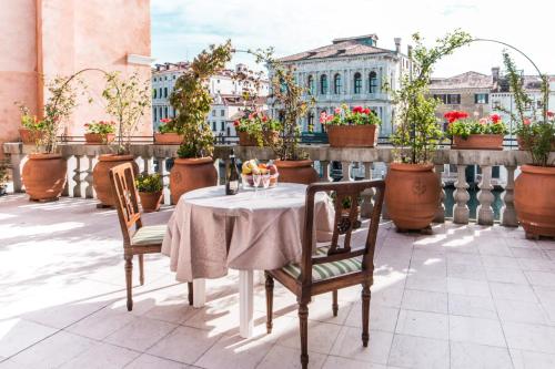 einen Tisch und Stühle auf einem Balkon mit Topfpflanzen in der Unterkunft Ca Zulian Venice - Grand Canal in Venedig