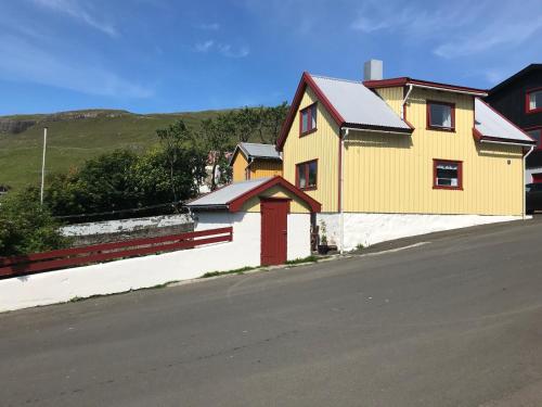 a yellow house on the side of a road at Cosy old house Vágar next to Mykines in Sørvágur