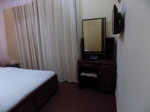 a bedroom with a bed and a dresser with a mirror at Belline Hotel Ishaka in Ishaka