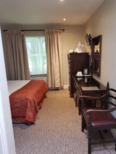 a bedroom with a bed and a desk and a mirror at JBs Bar & Guest Accommodation in Kilkenny