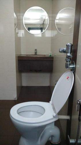 a bathroom with a white toilet and a mirror at Pals Hotel in Mumbai