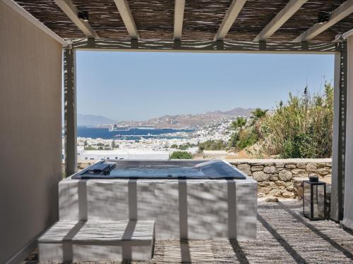 a table in a room with a view of the ocean at Belvedere Mykonos - Hilltop Rooms & Suites - The Leading Hotels of the World in Mýkonos City