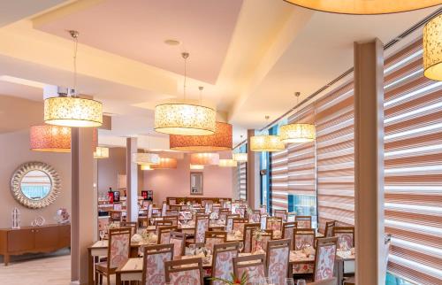 una sala da pranzo con tavoli e lampadari a braccio di West City Hotel a Cluj-Napoca