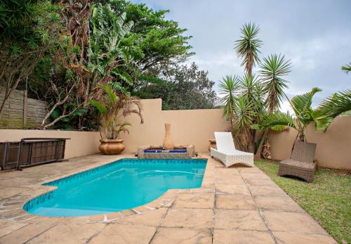 a swimming pool in a backyard with a chair and a table at Ekhaya Guest House in Ballito