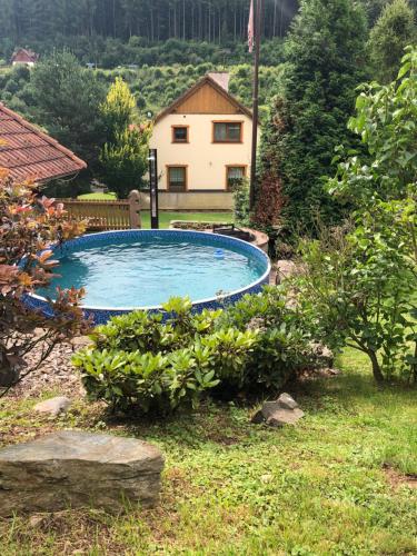 a swimming pool in a yard with a house in the background at Chalupa Pod Studánkou in Petříkovice
