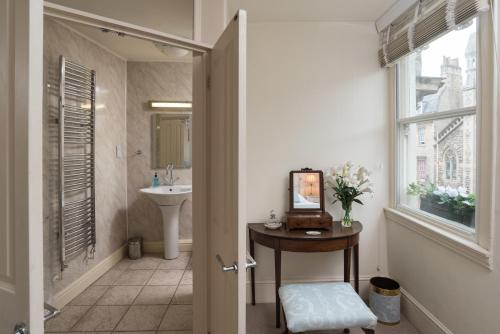 a bathroom with a sink and a table with a mirror at The Paragon Townhouse in Bath