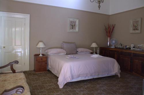 a bedroom with a bed and two lamps and a window at Bisibee Guest House in Oudtshoorn