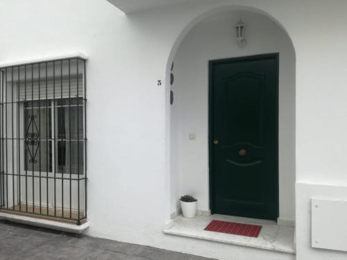 una puerta verde junto a una pared blanca con una puerta en La Fiammetta, en Vejer de la Frontera
