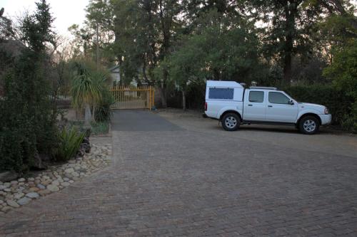 a white suv parked in a driveway at Bisibee Guest House in Oudtshoorn
