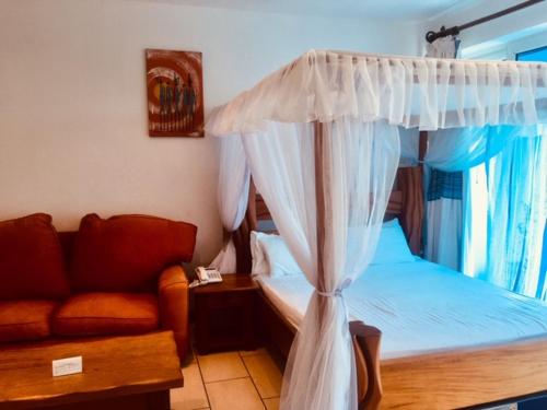 - une chambre avec un lit à baldaquin et un canapé dans l'établissement Bamburi Beach Studio Apartment B41, à Bamburi