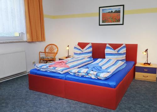 Un dormitorio con una cama roja y azul con almohadas a rayas en Pension Damköhler Thale OT Westerhausen, en Thale