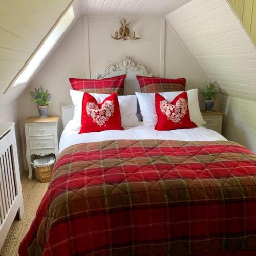 a red and white bed with red pillows on it at A Fairytale Highland Cottage in Aberfeldy